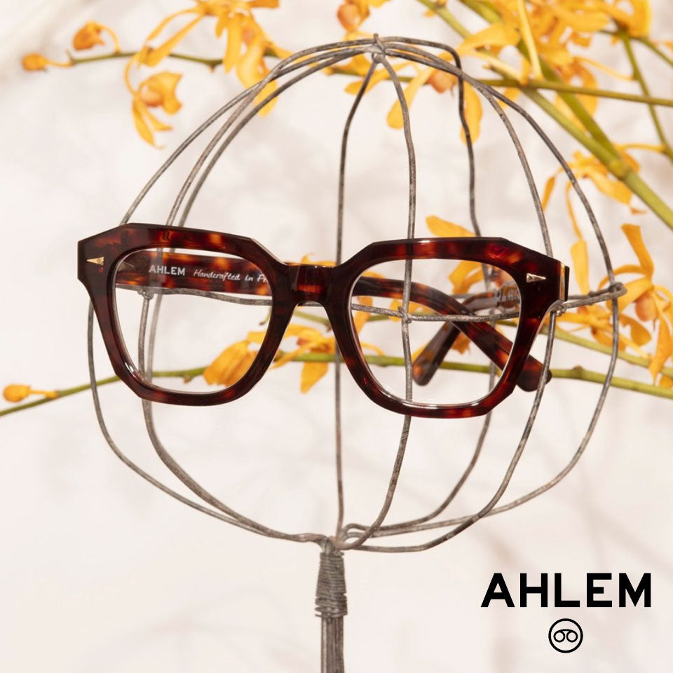 AHLEM Eyewear Pont des Art glasses frame hanging from a wire globe perched on a tree. 