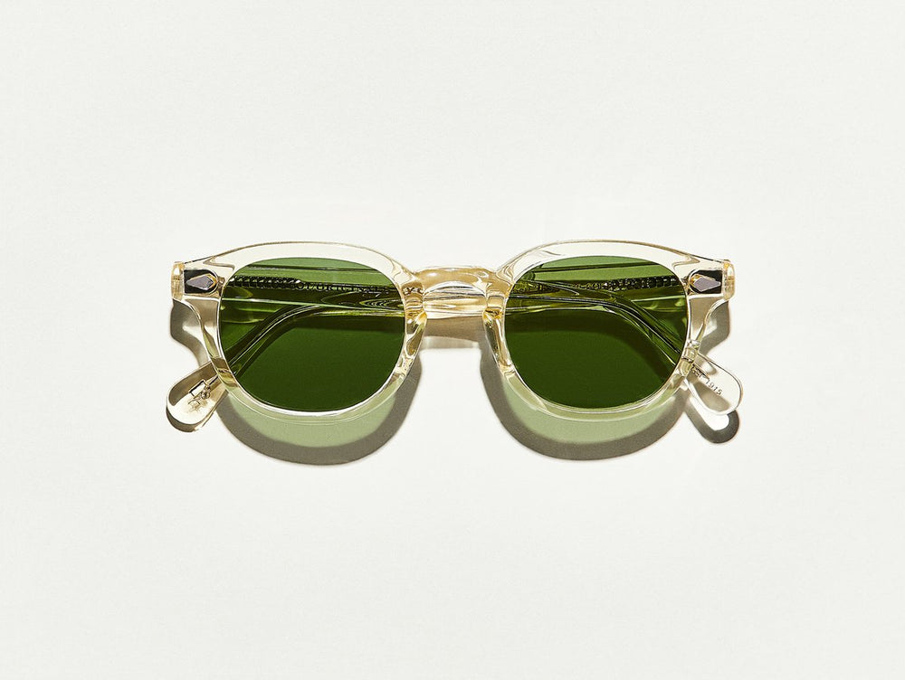 
                
                    Load image into Gallery viewer, Polished slightly yellow toned transparent acetate MOSCOT Lemtosh Sunglasses with green lenses front view
                
            